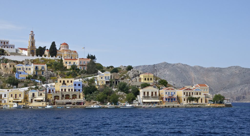 Image of the coast with homes on the water in Symi, Greece for travel