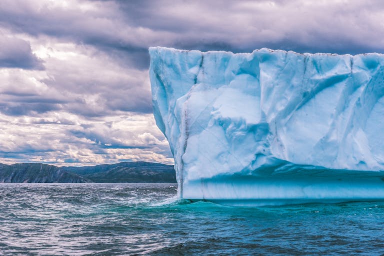 Majestic iceberg floating in the ocean with a dramatic sky, capturing the essence of nature's raw beauty.