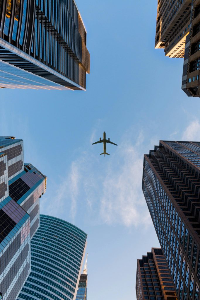 Airplane flying in sky over city buildings 